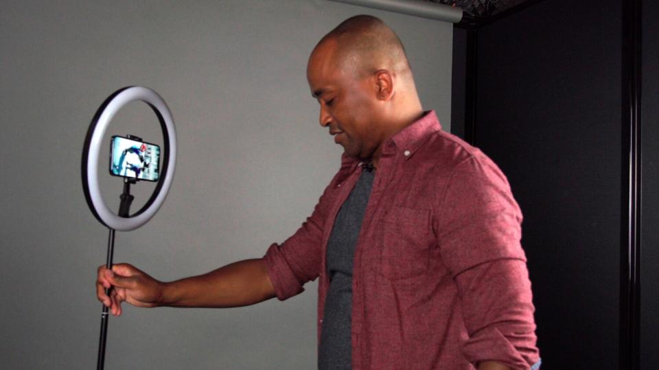 An actor sets up a ring light with a stand and holder for his phone in preparation for a self-taped audition.