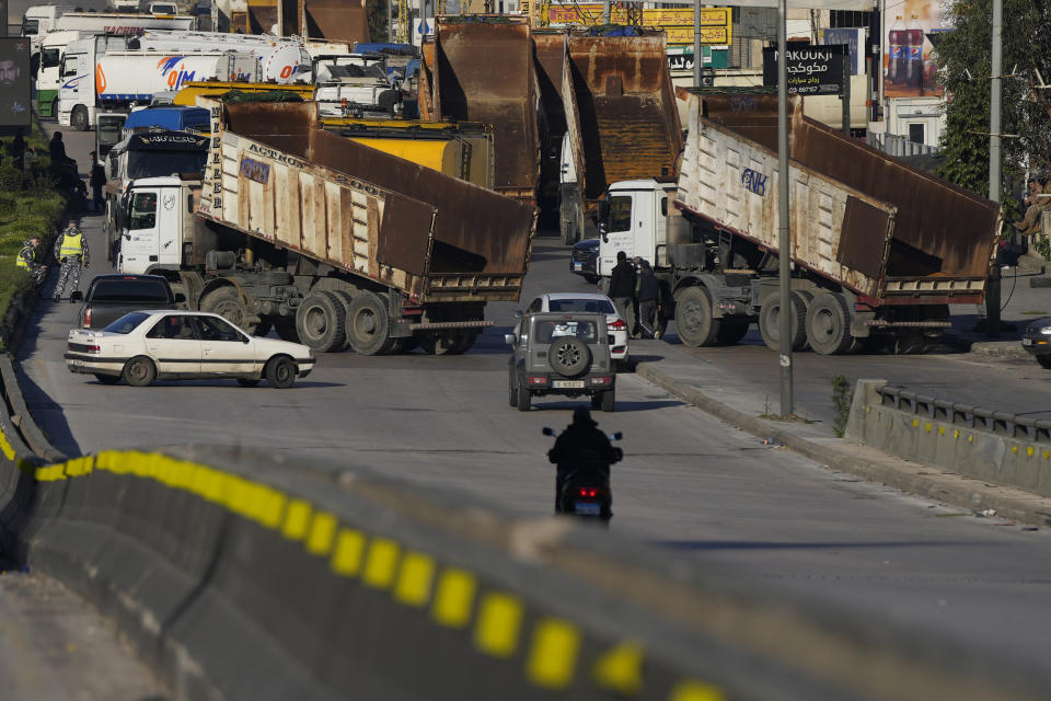 Dump trucks block a main highway during a general strike by public transport unions protesting the country's deteriorating economic and financial conditions in Beirut, Lebanon, Wednesday, Feb. 2, 2022. (AP Photo/Hassan Ammar)