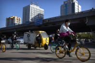 Commuters wearing face masks to protect against the coronavirus ride bicycles across an intersection in Beijing, Thursday, Oct. 22, 2020. The number of confirmed COVID-19 cases across the planet has surpassed 40 million, but experts say that is only the tip of the iceberg when it comes to the true impact of the pandemic that has upended life and work around the world. (AP Photo/Mark Schiefelbein)