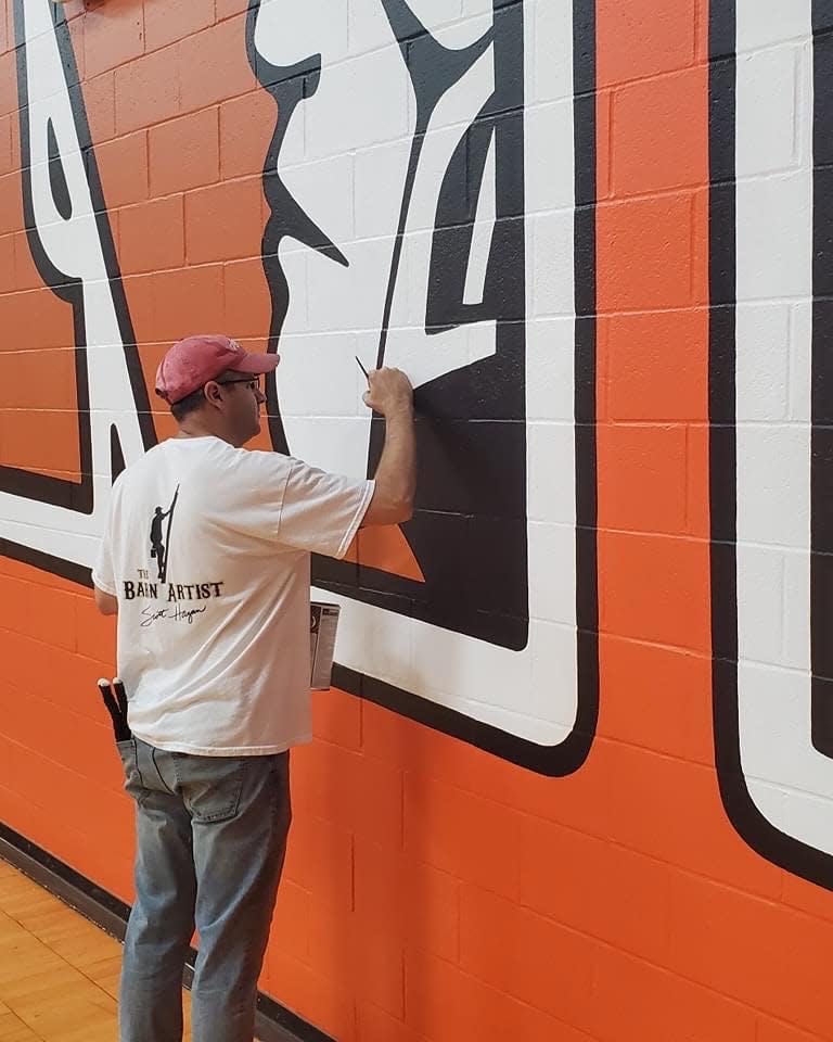 Scott Hagan, who's also known as "The Barn Artist," paints a mural at Newcomerstown High School that features 14-foot high letters and spans 100 feet.