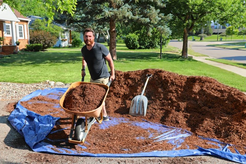 Man mulching yard and a large heap of mulch