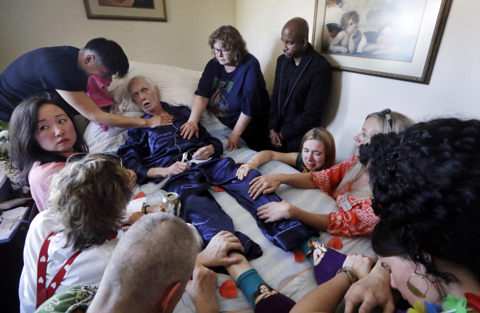 Robert Fuller lies unconscious after plunging drugs that will end his life into his feeding tube as his husband, Reese Baxter, upper left, and friends hold him, in Seattle on May 10, 2019. Fuller was one of about 1,200 people who have used Washington's Death with Dignity Act to end their lives in the decade since it became law. (AP Photo/Elaine Thompson)