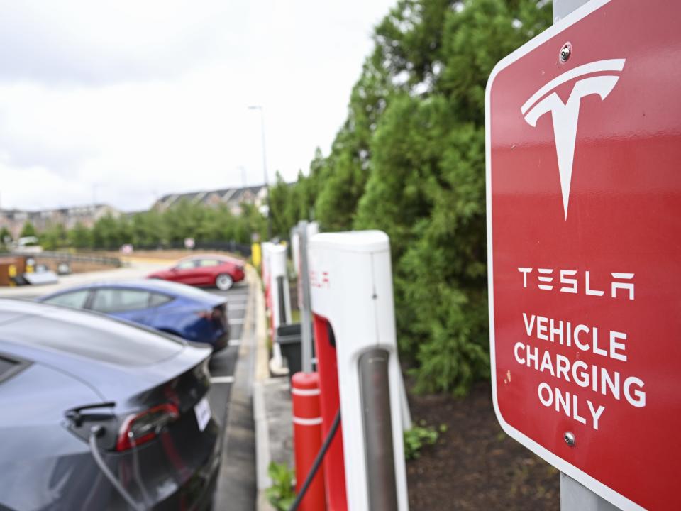 Several Tesla vehicles charge next to a sign that says "Tesla vehicle charging only"