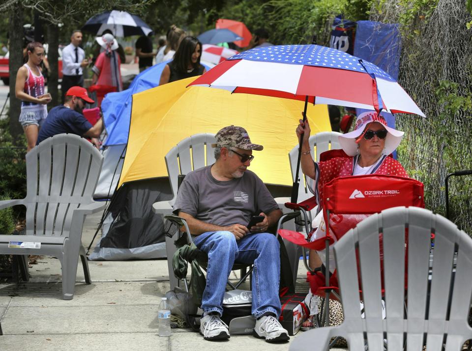 James DeWilde and Laureen Vartanian, from Port Orange, Fla., use a patriotic-theme beach umbrella to stay cool as supporters of President Donald Trump camp out in front of the Amway Center, Monday, June 17, 2019, ahead of Tuesday's 2020 campaign kick-off rally in Orlando, Fla. (Joe Burbank/Orlando Sentinel via AP)