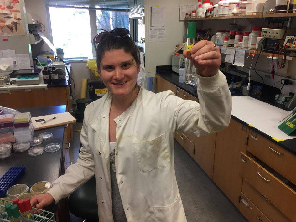 Morgan Vague holds up a test tube teeming with plastic-eating bacteria (Reed College)