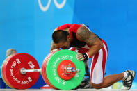 Sandow Weldemar Nasution of Indonesia kisses the weights as he competes in the men's 77kg weightlifting event during the Beijing 2008 Olympic Games. Weldemar Nasution's colorful arm tattoo features a dragon. (Photo by Phil Walter/Getty Images)