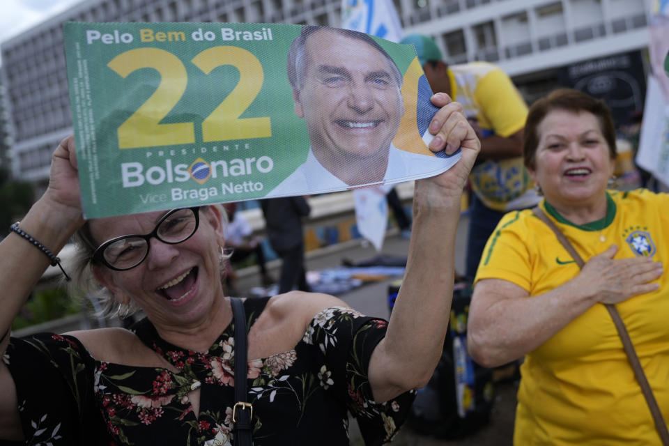 Supporters show signs with the image of Brazil's President Jair Bolsonaro, who is running for reelection, during a campaign event at the bus station in Brasilia, Brazil, Thursday, Oct. 27, 2022. Bolsonaro is facing former president Luiz Inacio Lula da Silva in a presidential run-off election set for Oct. 30. (AP Photo/Eraldo Peres)