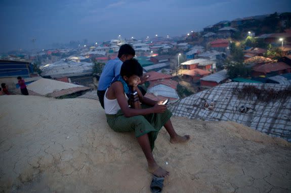 Rohingya Muslims use their cellphones as they sit on a hill overlooking Balukhali refugee camp, in Bangladesh.