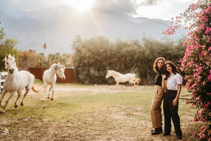 The couple outdoors with horses running around them