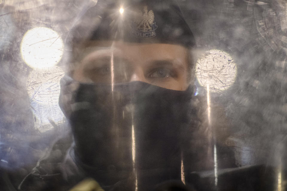 A riot policeman stands behind a shield during a protest against a top court ruling restricting abortions in Warsaw, Poland, Wednesday, Nov. 18, 2020. Polish police came under criticism for using tear gas and force on mostly female and young protesters during the latest in a string of women-led protests against a top court ruling restricting abortion. (AP Photo/Agata Grzybowska)