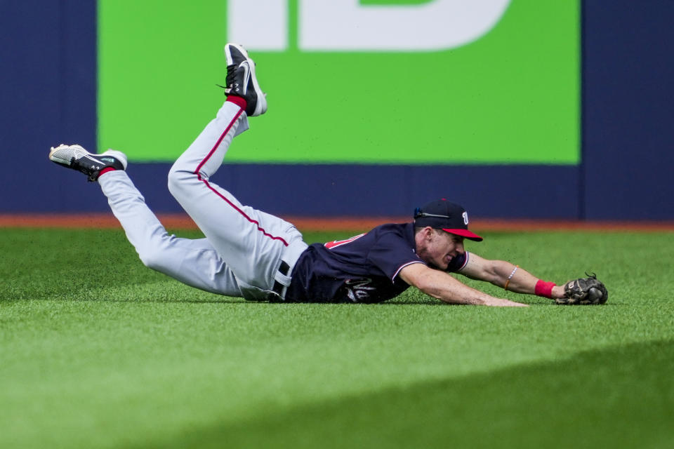 Washington Nationals center fielder Jacob Young (30) makes a diving catch against Toronto Blue Jays shortstop Ernie Clement during the second inning of a baseball game in Toronto on Wednesday, Aug. 30, 2023. (Andrew Lahodynskyj/The Canadian Press via AP)