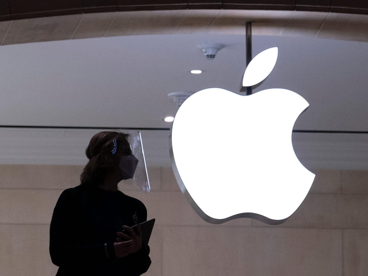 An Apple store employee's dark silhouette next to a white glowing Apple logo