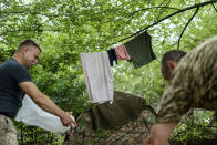 Laundry hangs on a clothesline as a member of the Dnipro-1 regiment cleans his tent during a period of relative calm around their position near Sloviansk, Donetsk region, eastern Ukraine, Friday, Aug. 5, 2022. While the lull in rocket strikes has offered a reprieve to remaining residents, some members of the Ukrainian military unit say it could be a prelude to renewed attacks. (AP Photo/David Goldman)