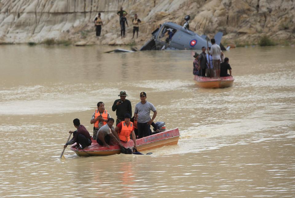 Rescue workers travel in a boat as they drag a body found at the site where a Cambodian military helicopter crashed on the outskirts of Phnom Penh July 14, 2014. The military helicopter crashed on Monday, killing five and injured one, police told Reuters. A Cambodian air force official said authorities are still investigating the cause of the crash. (REUTERS/Samrang Pring)