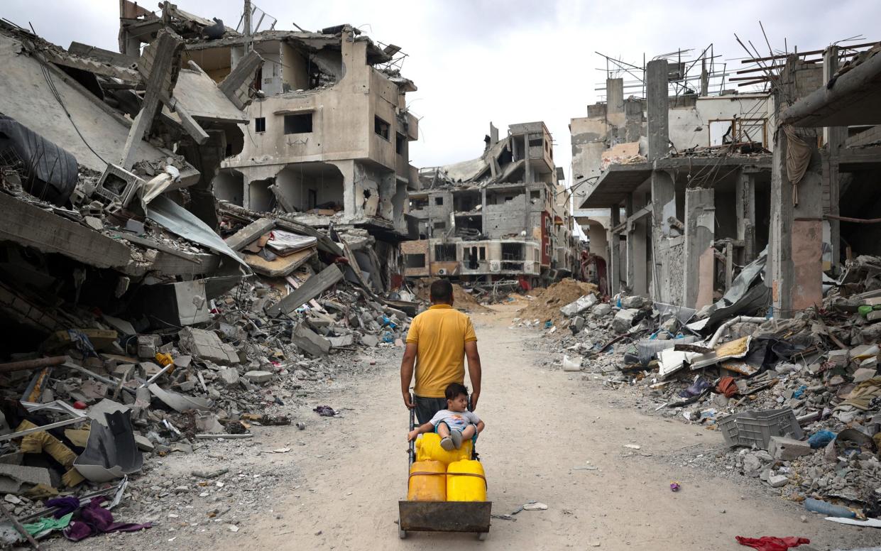 A Palestinian man pulls a cart on a road lined with destroyed buildings in Khan Yunis in the southern Gaza Strip