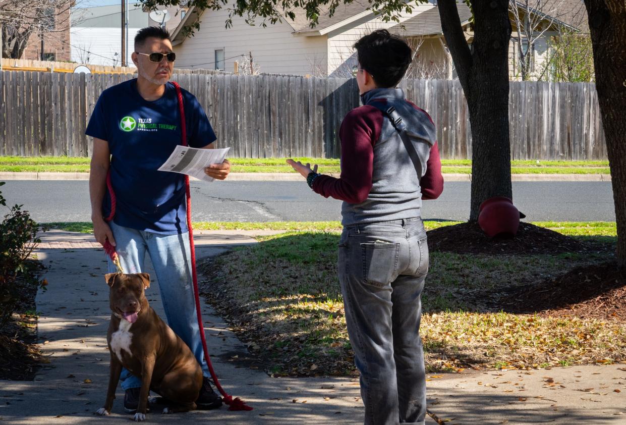 Miriam Dorantes, a constituent liaison for Council Member Fuentes, right, gives a flyer to neighborhood resident Ramón Alamán, left, while door knocking in Del Valle to gauge interest and gather opinions on bringing a city-sponsored food co-op to the low-income neighborhood that lacks a nearby grocery store, Saturday, Feb. 24, 2024.