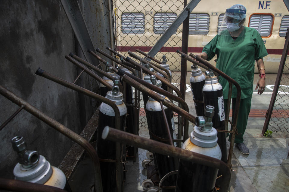 A health worker checks oxygen cylinders stored next to a train prepared as COVID-19 care centre in the wake of spike in the number of positive coronavirus cases, at a railway station in Gauhati, India, Thursday, May 6, 2021. Infections in India hit another grim daily record on Thursday as demand for medical oxygen jumped seven-fold and the government denied reports that it was slow in distributing life-saving supplies from abroad. (AP Photo/Anupam Nath)