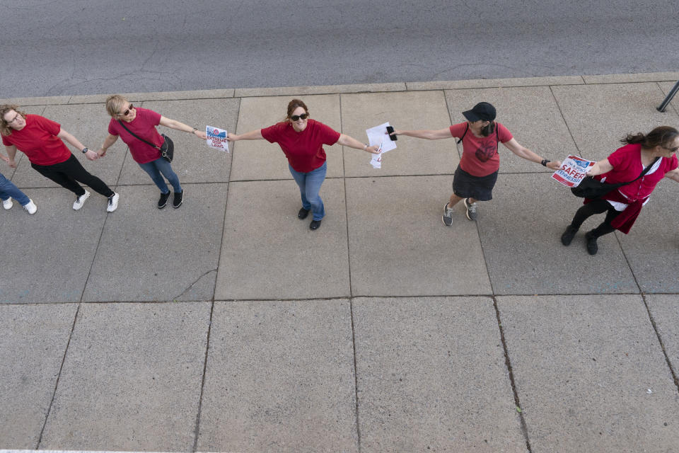 Demonstrators hold hands and lock arms with each other during a protest for gun control legislation, Tuesday, April 18, 2023, in Nashville, Tenn. Participants created a human chain spreading from Monroe Carell Jr. Children's Hospital at Vanderbilt, where victims of The Covenant School shooting were taken on March 27, to the Tennessee State Capitol. (AP Photo/George Walker IV)