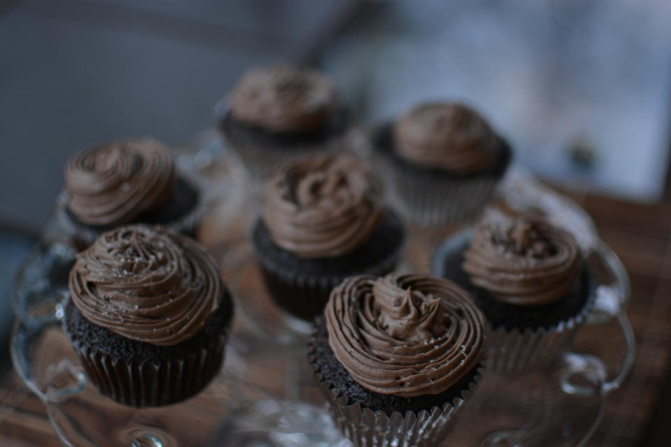 Seven chocolate cupcakes with frosting arranged on a glass platter