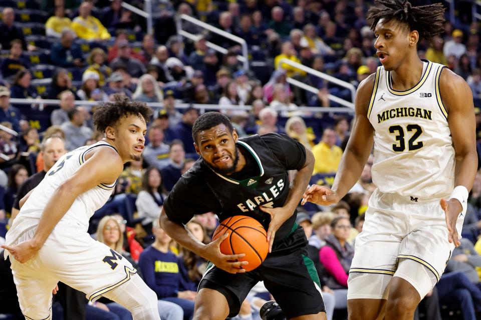 Dec 16, 2023; Ann Arbor, Michigan, USA; Eastern Michigan Eagles guard Tyson Acuff (5) dribbles defended by Michigan Wolverines forward Terrance Williams II (5) and forward Tarris Reed Jr. (32) in the second half at Crisler Center.