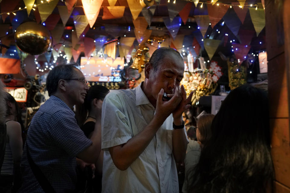 A man plays his harmonica while drinking in a bar at the Golden Gai in the Shinjuku district of Tokyo, July 26, 2019. (AP Photo/Jae C. Hong)