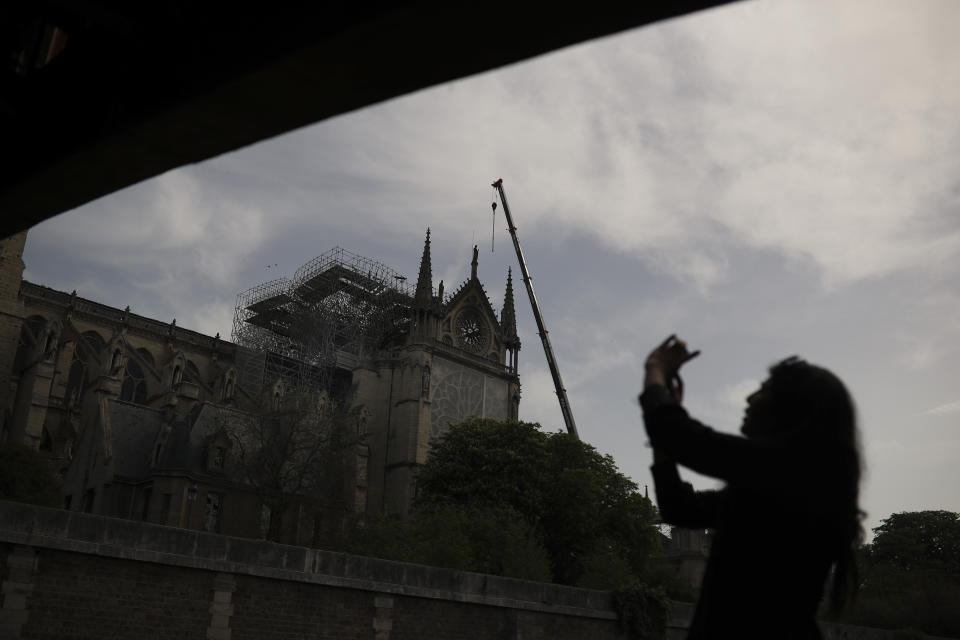 A woman takes photographs of the Notre Dame cathedral in Paris, Monday, April 22, 2019. In the wake of the fire last week that gutted Notre Dame, questions are being raised about the state of thousands of other cathedrals, palaces and village spires that have turned France — as well as Italy, Britain and Spain — into open air museums of Western civilization. (AP Photo/Francisco Seco)