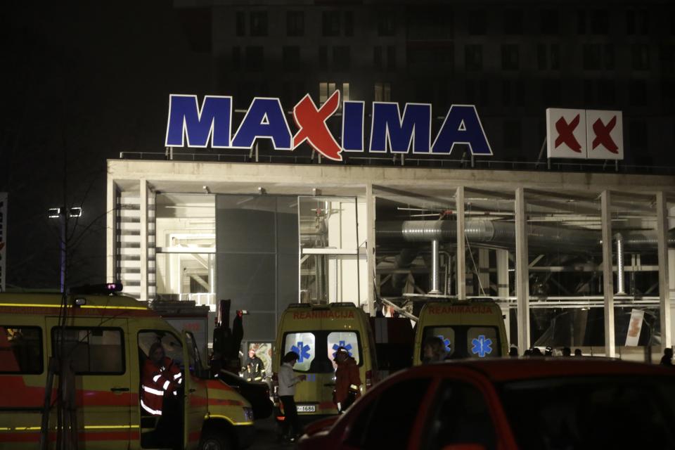 Ambulances are pictured parked near a store with a collapsed roof in Riga