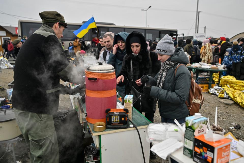 Ukrainian refugees get hot drinks as they wait in freezing cold temperatures to get on a bus, after crossing the Ukrainian border into Poland. (Getty)