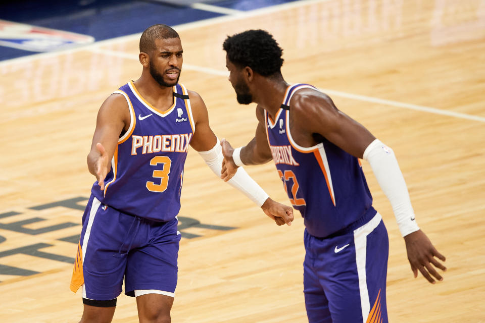 Chris Paul and Deandre Ayton go to slap hands in celebration during a game.