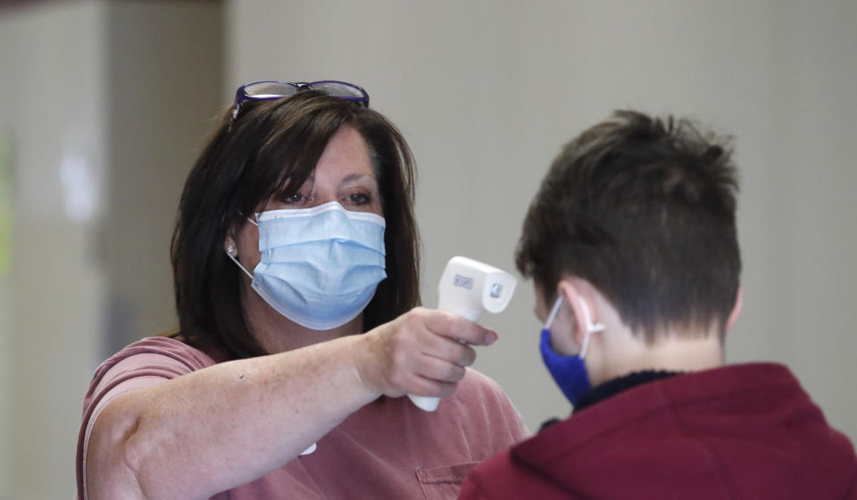 Una maestra en Texas toma la temperatura a un estudiante durante un curso de verano. El debate sobre cuándo, cómo y cuánto reabrir las escuelas el próximo curso escolar es tenso en Estados Unidos. (AP Photo/LM Otero)