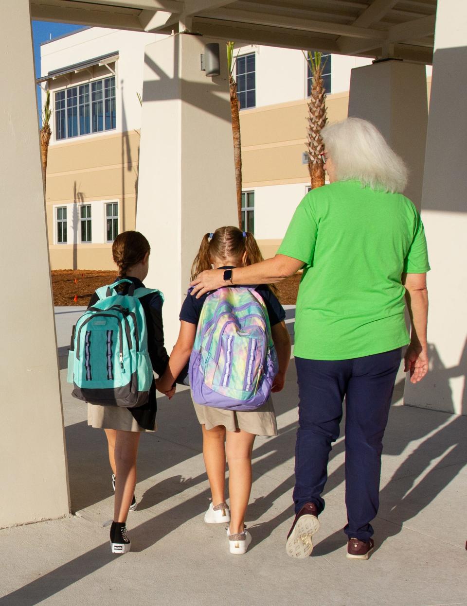 Andy King, a pre-kindergarten teacher at South Pointe Elementary, escorts two students toward the school's entrance Friday morning. It was the first day of classes for students in Polk County.