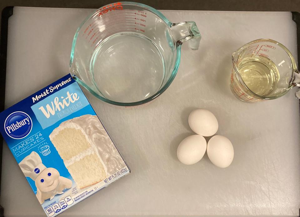 A pillsbury boxed cake mix on a white tray with measuring cups with oil and water and eggs