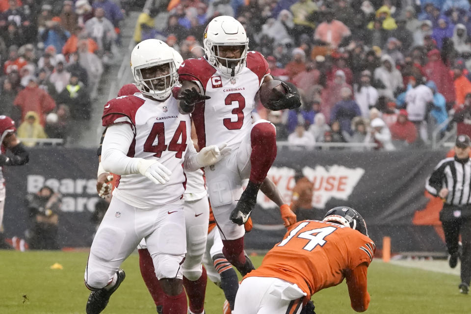 Arizona Cardinals safety Budda Baker (3) leaps over Chicago Bears quarterback Andy Dalton after Baker intercepted a Dalton pass during the first half of an NFL football game Sunday, Dec. 5, 2021, in Chicago. Running with Baker is Markus Golden. (AP Photo/David Banks)