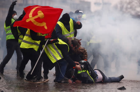 Protesters wearing yellow vests help a person injured by a water cannon during a demonstration by the "yellow vests" movement near the Arc de Triomphe in Paris, France, January 12, 2019. REUTERS/Christian Hartmann