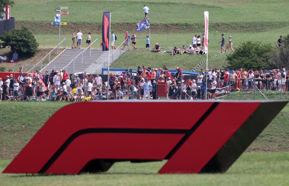 Spectators are seen behind a large Formula One F1 logo ahead of the Formula One Hungarian Grand Prix at the Hungaroring race track in Mogyorod near Budapest on August 1, 2021. (Photo by FERENC ISZA / AFP) (Photo by FERENC ISZA/AFP via Getty Images)