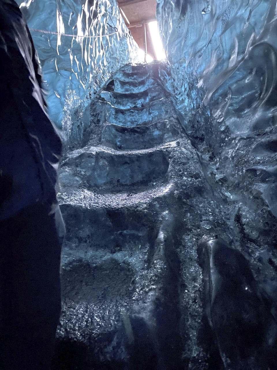 This Nov. 18, 2023 image provided by Beth Harpaz shows a staircase carved from ice that visitors must climb up and down to tour an ice cave at Vatnajokull National Park, located on an ice field in southeastern Iceland. The caves can only be explored on a tour with a registered guide. Winter crampons must be attached to shoes and boots to avoid slipping. (Beth Harpaz via AP)