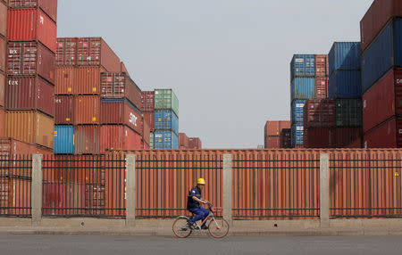 A worker cycles past containers outside a logistics center near Tianjin Port, in northern China, May 16, 2019. REUTERS/Jason Lee/Files