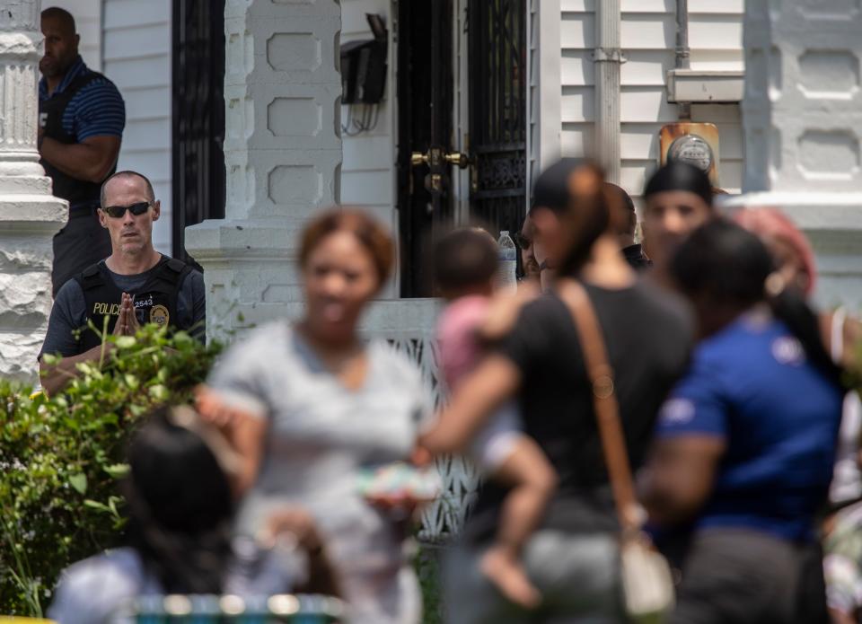 Law enforcement members stand guard as loved ones gather at a home on 37th Street where an officer involved shooting death began. May 20, 2022