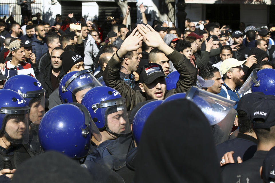Riot police hold back demonstrators as they march in the streets of the Algerian capital, Algiers, to denounce President Abdelaziz Bouteflika's bid for a fifth term, Friday, Feb. 23, 2019. The 81-year-old Bouteflika announced this month that he plans to seek a new term in April presidential elections despite serious questions over his fitness for office after a 2013 stroke left him largely infirm. (AP Photo/Anis Belghoul)