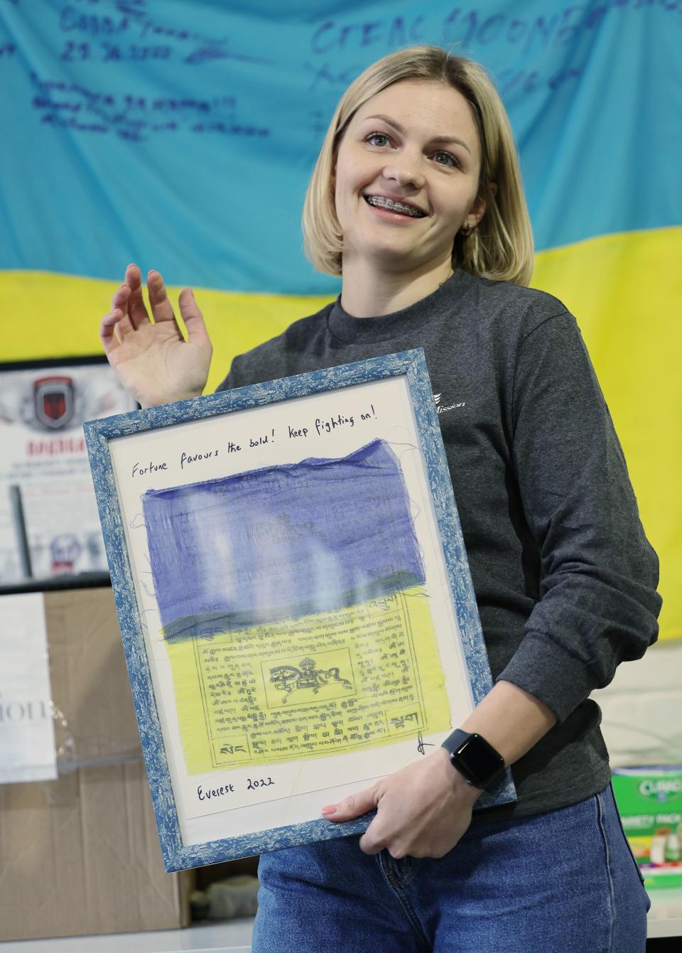 Viktoriia Tarasiuk, country manager for Ukraine and director of the August Mission Foundation of Ukraine, shows a few items she keeps at her workstation with friends and delegation members while at their small warehouse in Khmelnytskyi, Ukraine, on Monday, May 1, 2023. | Scott G Winterton, Deseret News