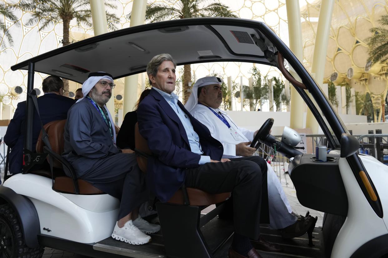 John Kerry rides in a cart.