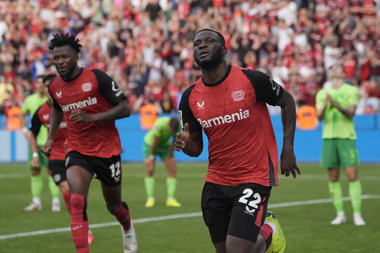 Leverkusen's Victor Boniface, right, celebrates after he scored during the German Bundesliga soccer match between Bayer Leverkusen and VfL Wolfsburg at the BayArena in Leverkusen, Germany, Sunday, Sept. 22, 2024. (AP Photo/Martin Meissner)