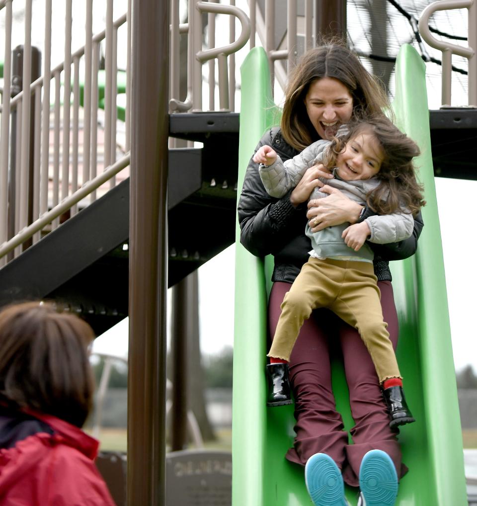 Sarah Cua of Columbus, formerly of North Canton, gives her gleeful daughter, Stella Cua, 4, a ride down the slide at the Dogwood Possibility Playground in North Canton during a holiday visit with her parents, Lori and Tim McCort of North Canton.