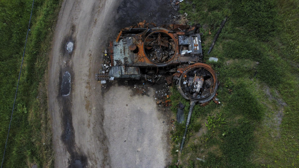 The gutted remains of a tank lie by a road in Lypivka, on the outskirts of Kyiv, Ukraine, Tuesday, June 14, 2022. (AP Photo/Natacha Pisarenko)