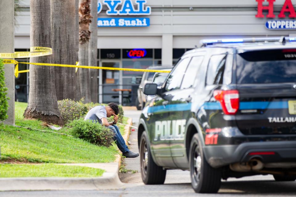 A man holds his head in his hands as he sits on the curb while the Tallahassee Police Department investigates a double homicide following a shooting just before at the McDonaldÕs located on West Pensacola Street on Thursday evening, June 22, 2023. 