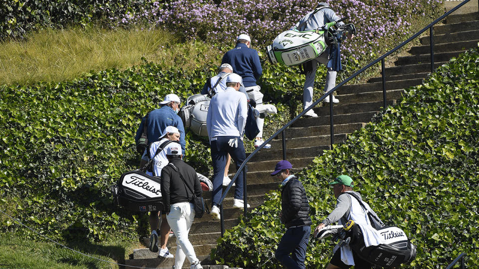 Golfers, caddies and staff, pictured here returning to the clubhouse after play was suspended.