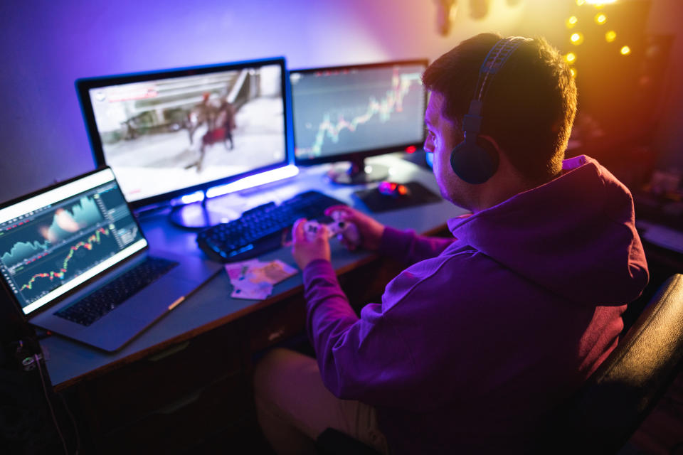 Male gamer sitting at home and playing NFT games online for money.