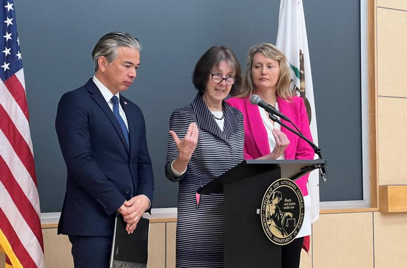 De izquierda a derecha: el fiscal general de California Rob Bonta, la senadora estatal de California Nancy Skinner y la asambleísta Buffy Wicks de pie en un podio en un salón de clases.