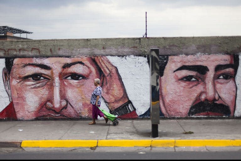 A woman walks in front of a graffiti depicting Venezuelan late President Hugo Chavez (L) and Venezuelan President Nicolas Maduro (R) in Caracas on April 17, 2013