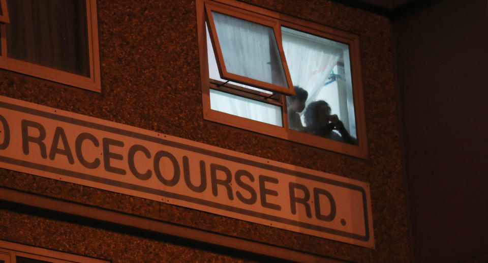 Residents watch out the window of a unit inside a tower on Racecourse Road on Saturday evening. Source: AAP 